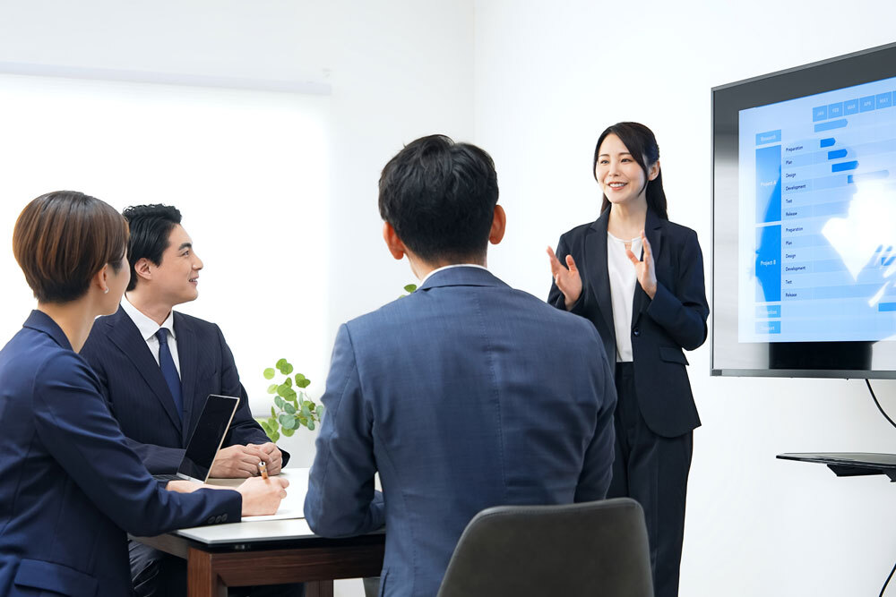 担当者が顧客企業のオフィスでホワイトボードを使いながらプレゼンしている写真